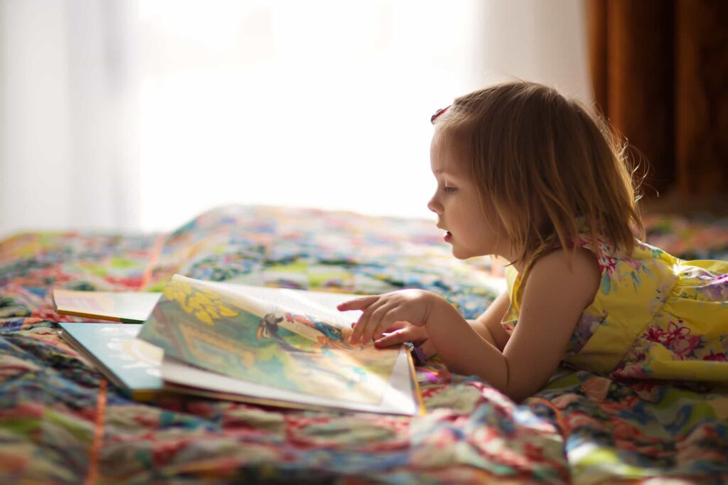 Meisje leest een prentenboek op bed
